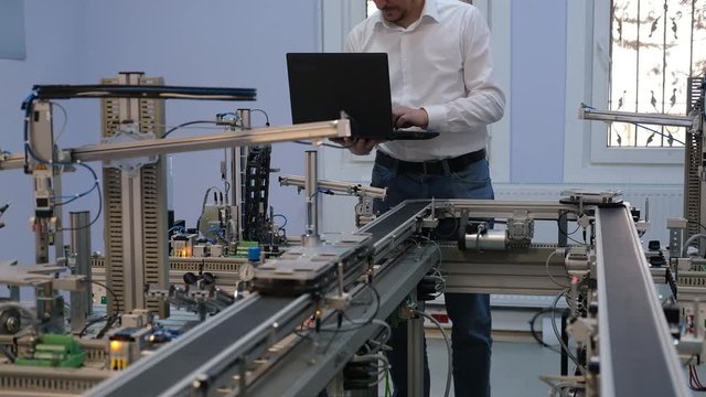 Industry 4.0 concept; Engineer is working on laptop to program smart factory prototype's automation. automated car on production line, artificial intelligence in smart manufacturing.