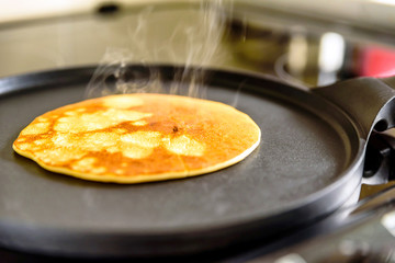 pancake frying pan with crepe pancake cooking on cooker in kitchen