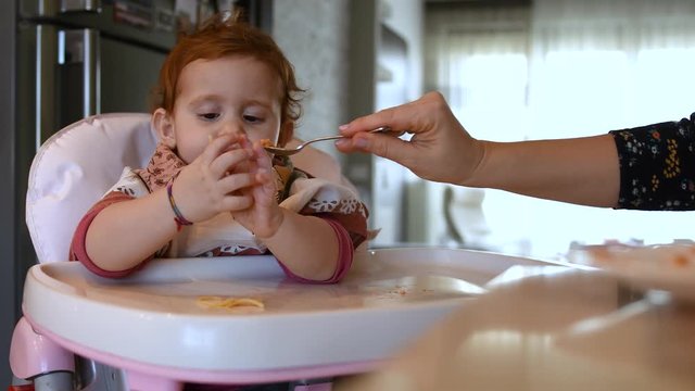 Little female girl plays with spaghetti with sauce while eating