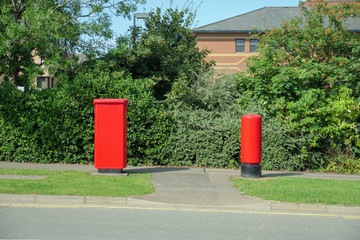 Fototapeta na wymiar british red post boxes over bushes in england uk