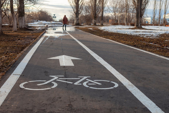 Bike path sign on the asphalt. Mud and snow. Russia