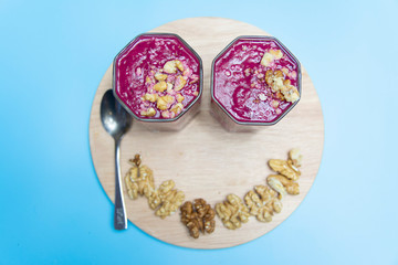 cranberry smoothie on a blue background with slices of nuts