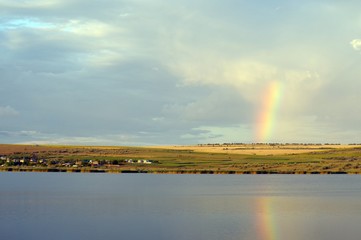 Lake reeds village and rainbow