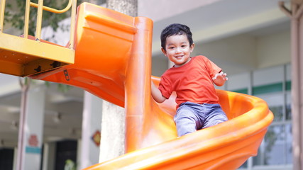 Cute little Asian 2 year old toddler baby boy child playing on a slide at indoor playground in department store, Baby Sliding Down Slide, Kid first experience concept.