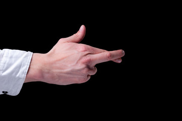 Human hand in a white shirt to cross one's fingers is a hand gesture commonly used to wish for luck on isolated black background
