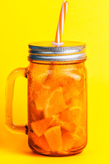 Yellow glass jug with handle with cold natural drink with pieces of fruit