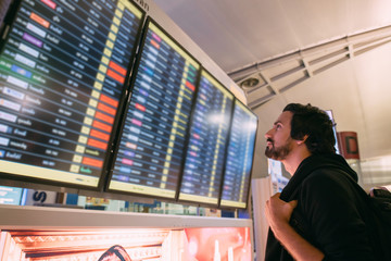 A man near the schedule board at the airport