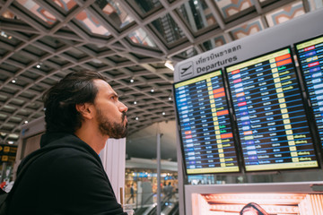 A man near the schedule board at the airport.