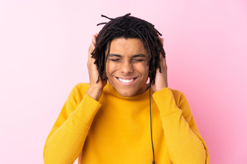 Young African American man listening music over isolated pink wall