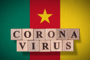 Flag of Cameroon with wooden cubes spelling coronavirus on it. 2019 - 2020 Novel Coronavirus (2019-nCoV) concept, for an outbreak occurs in Cameroon.
