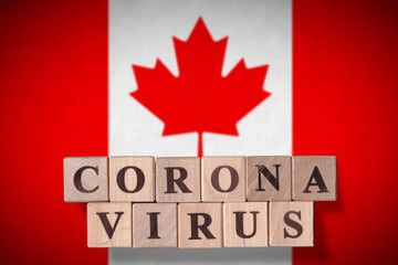 Fototapeta na wymiar Flag of Canada with wooden cubes spelling Coronavirus on it. 2019 - 2020 Novel Coronavirus (2019-nCoV) concept, for an outbreak occurs in Canada.