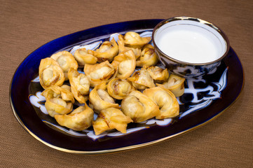 Oriental-style fried dumplings with sour cream in a bowl
