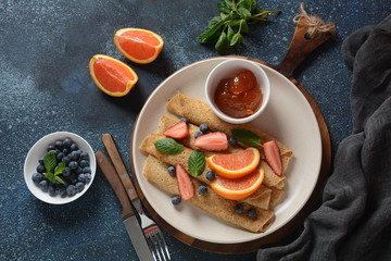 Sweet pancakes wrapped with fresh mint, strawberries, blueberries, oranges and jam. Healthy breakfast concept