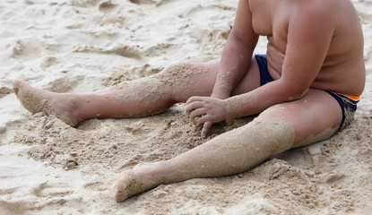 A boy is playing in the sand of a beach.