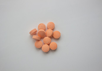 Medical tablets under a magnifying glass on a white background.