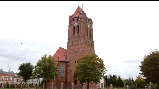 Saint Wojciech parish in Prabuty. Gothic red brick church with high bell tower on a sunny autumn day.
