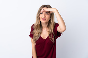 Young woman over isolated white background looking far away with hand to look something