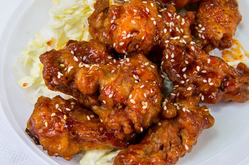 Chicken wings in a sauce with fresh cabbage and sesame seeds