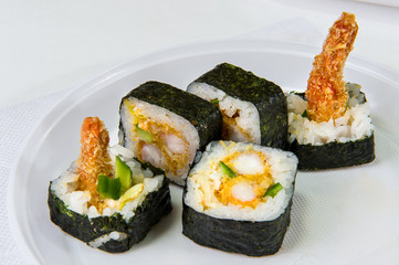 Japanese rolls with rice, seaweed, king prawns and cucumber on a disposable plastic plate on a white background