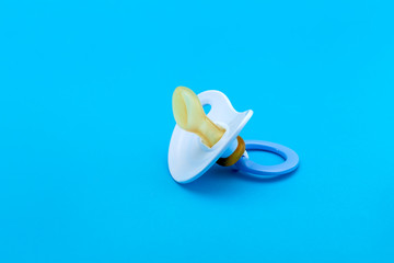 a blue pacifier made of soft silicone  isolated on blue background side view with copy space.