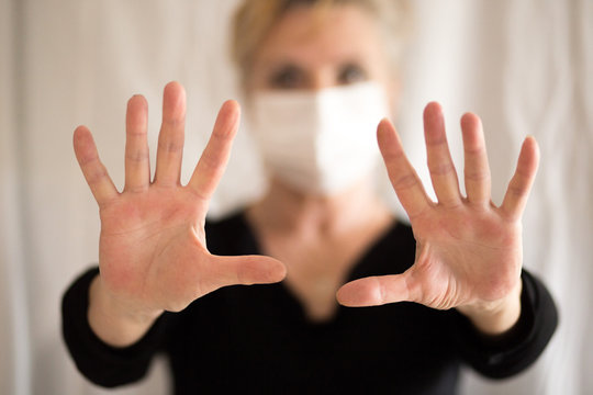Senior woman wearing mask, shows clean hands and show stop hands. Selective focus.