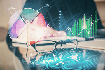 Forex chart hologram on hand taking notes background. Concept of analysis. Double exposure