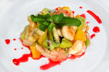 Dessert. Pieces of bananas, kiwi, pineapple, covered with red sweet caramel and decorated with a sprig of mint