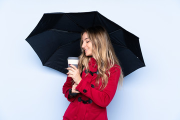Young woman with winter coat holding an umbrella and a coffee to take away