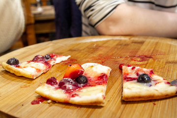 Half-eaten pizza, pie with berries in the cafe. The visitor gorged himself.