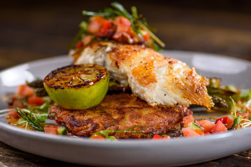 A serving of Grilled Snapper fish with Asparagus, Roasted Potato, grilled lemon and salsa