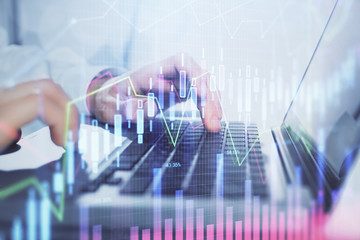 Double exposure of market chart with man working on computer on background. Concept of financial analysis.