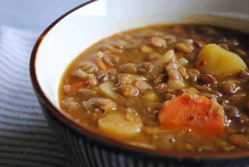 Healthy Vegan Lentil Soup with Carrot and Potatoes in a brown bowl. Close up view.
