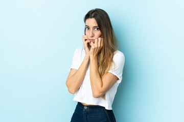 Fototapeta premium Young caucasian woman over isolated background nervous and scared putting hands to mouth