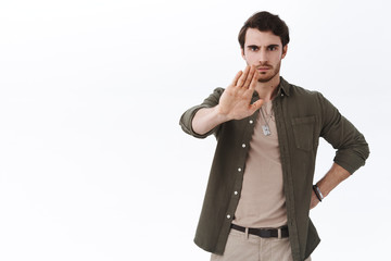 Serious-looking male boss team lead raising hand up to say stop, frowning give warning, disagree...