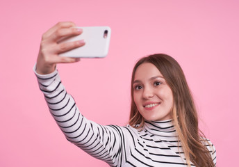 Beautiful caucasian girl in a striped sweater makes selfie