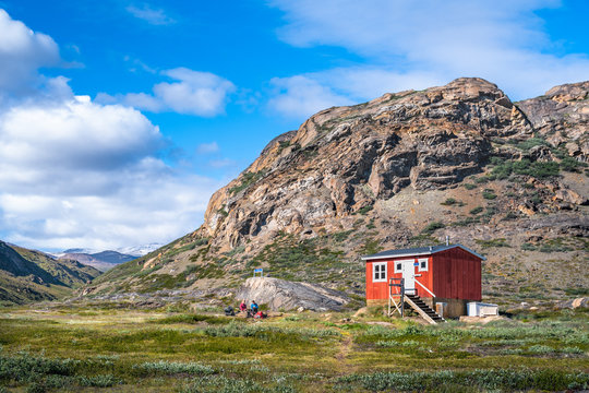 Red emergency shelter in front of a hill on the Arctic Circle Trail, Grenland