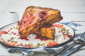 French toast stuffed with cream cheese, served with berry coulis, fresh strawberries and cookie crumble