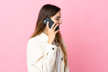 Young caucasian woman isolated on pink background keeping a conversation with the mobile phone with someone