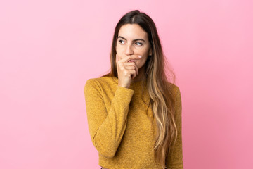 Fototapeta premium Young caucasian woman isolated on pink background having doubts and with confuse face expression