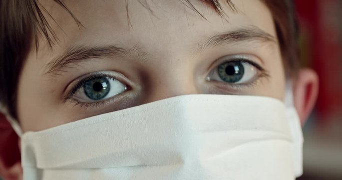 Extreme close up of boy wearing protection mask looking at camera. Eye level, push out, hand-held, single shot, extreme close up, 4K.