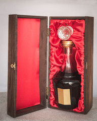 liquor in fancy crystal bottle packaged in elegant oak wood box with red cloth