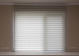 Pleated blinds XL, white color, with 50mm fold close up in the window opening in the interior. Luxury sun protection and window decoration. Modern shades.