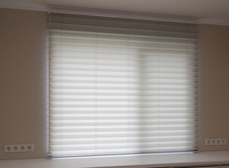 Pleated blinds XL , white color, with 50mm fold close up in the window opening in the interior. Luxury sun protection and window decoration. Modern shades.