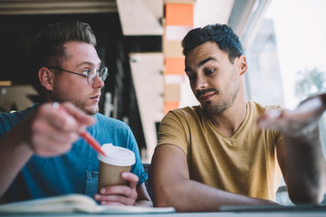 Successful young male coworkers discussing business ideas in cafe
