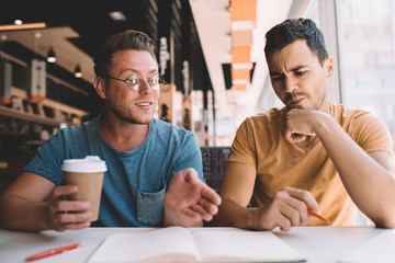 Inspired male colleagues discussing business plan in cafe