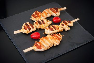 Skewered on wooden sticks tasty chicken meat and cherry tomatoes