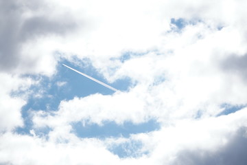 Fototapeta na wymiar White light fluffy clouds in a blue sky with a solar flare.