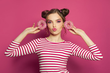 Fototapeta premium Fashion woman holding donut on colorful pink background, diet concept