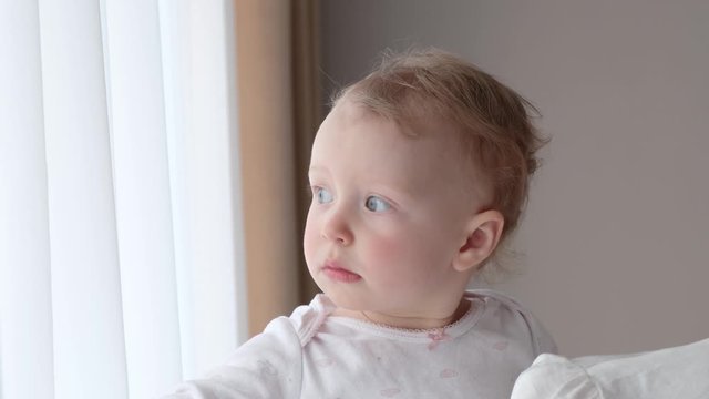A little girl in her mother’s arms near the window. Slow motion, 4K video.