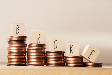 Wooden cubes with the word broke and pile of coins, money climbing stairs, business concept